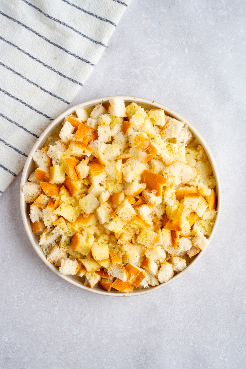 A small bowl of stuffing tossed in a butter mixture. The bowl is on a white counter with a white striped napkin.