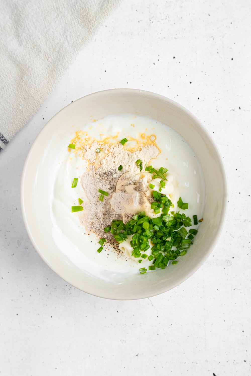 A bowl of sour cream, chives, and seasonings.
