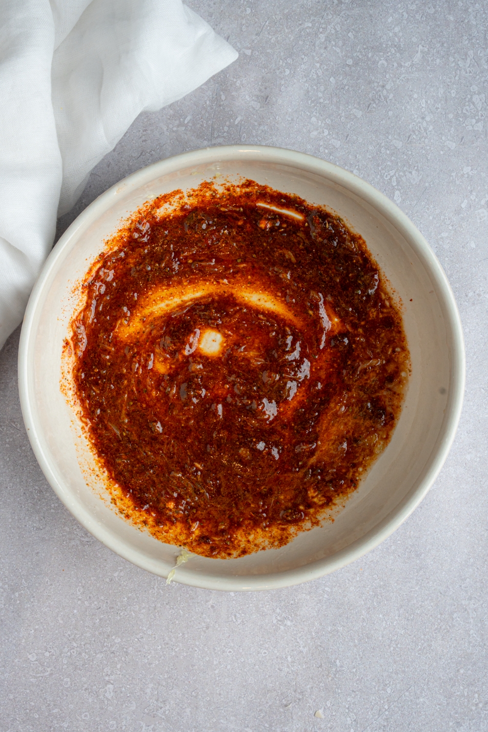 A white bowl with a fiesta lime marinade. The bowl is on a white counter with a white cloth napkin.
