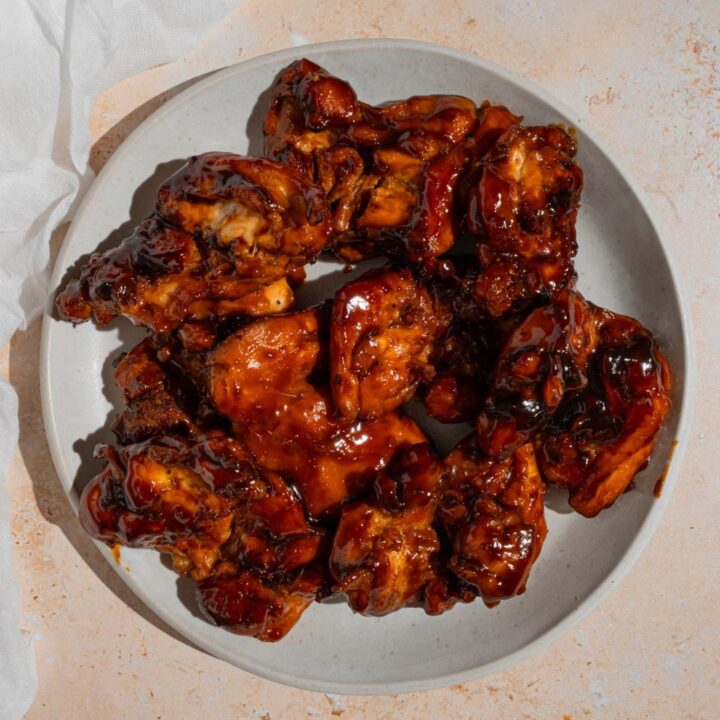 Grilled Hawaiian BBQ chicken on a white plate. The plate is on a tan counter with a white cloth napkin.