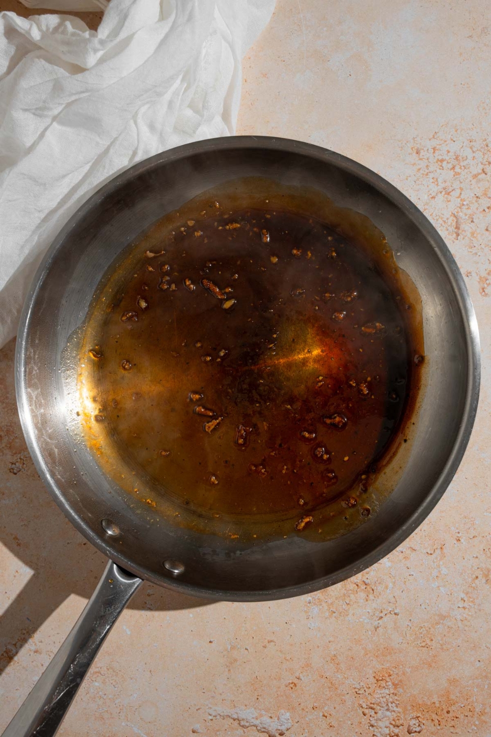Hawaiian BBQ marinade cooking in a frying pan. The pan is on a tan counter with a white cloth napkin.